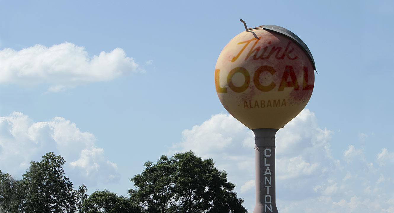 a large peach sculpture sits on a stand with the name Clanton on the side