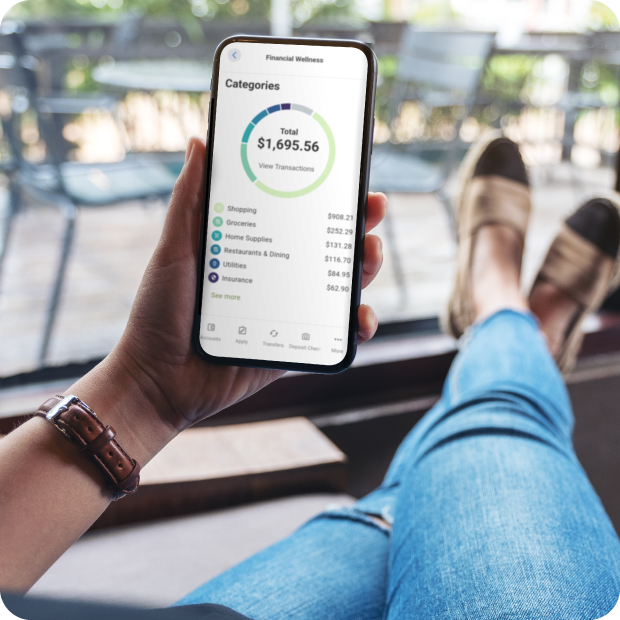 A Guardian Credit Union Member is enjoying home porch, feet propped up comfortably while engaged with the Guardian Credit Union App on their smartphone, focusing on her financial wellness.