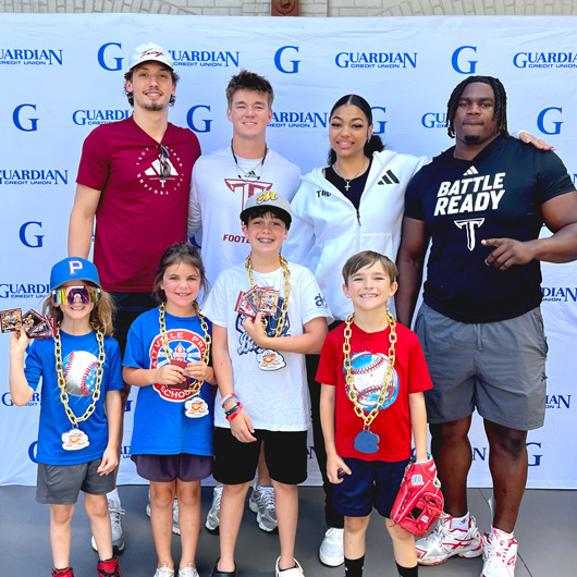 Celebrating the 2nd Annual Guardian Day at the Biscuits, featuring Troy University athletes joyfully engaging with enthusiastic young fans!