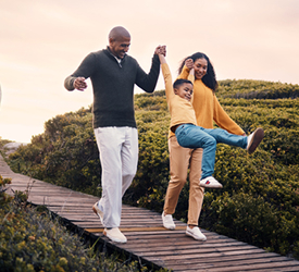 Smiling family walking together outdoors, representing Guardian CU’s commitment to protecting what matters most with life insurance