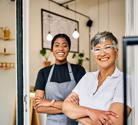 Two women standing confidently in their shop, representing Guardian CU’s Insurance Services for business protection and coverage