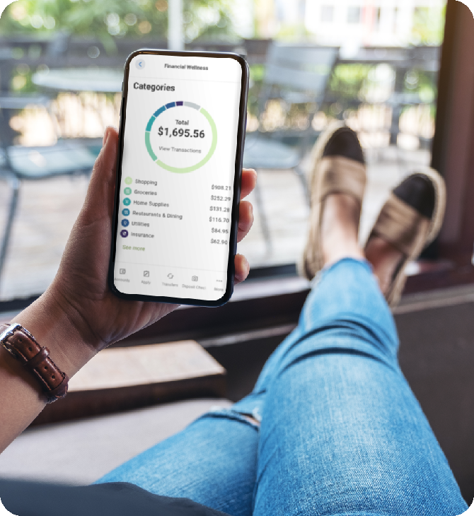 A Guardian Credit Union Member is enjoying home porch, feet propped up comfortably while engaged with the Guardian Credit Union App on their smartphone, focusing on her financial wellness.