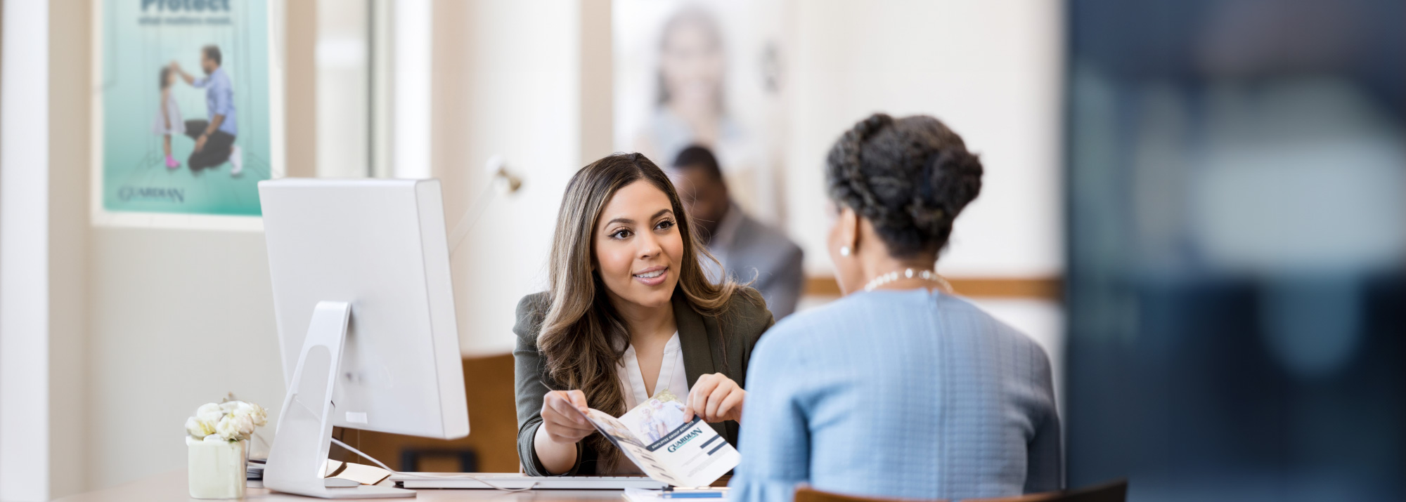 Guardian Credit Union Insurance Expert presents the Business Employee Benefits folder to a client in a Branch office.