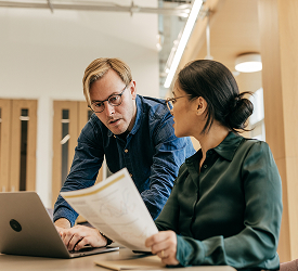 Two professionals reviewing documents, representing Guardian Credit Union’s employee group benefits and workplace coverage options