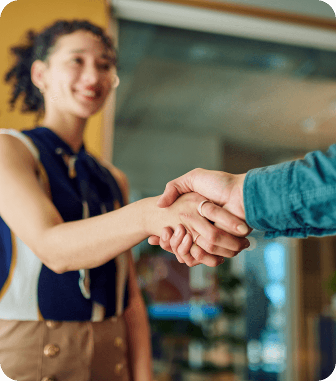 Smiling woman shaking hands in a professional setting, representing trust and member relationships