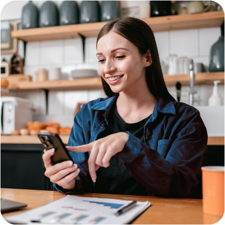 Young woman checks phone for Guardian Credit Union direct deposit, reviewing financial charts at home