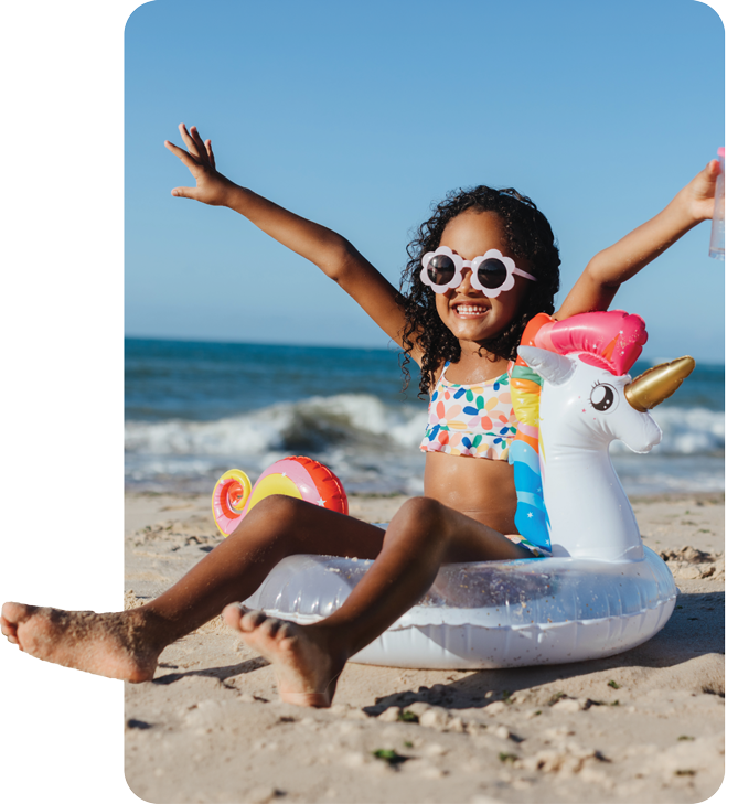 A happy girl is enjoying the beach on her unicorn inflatable.