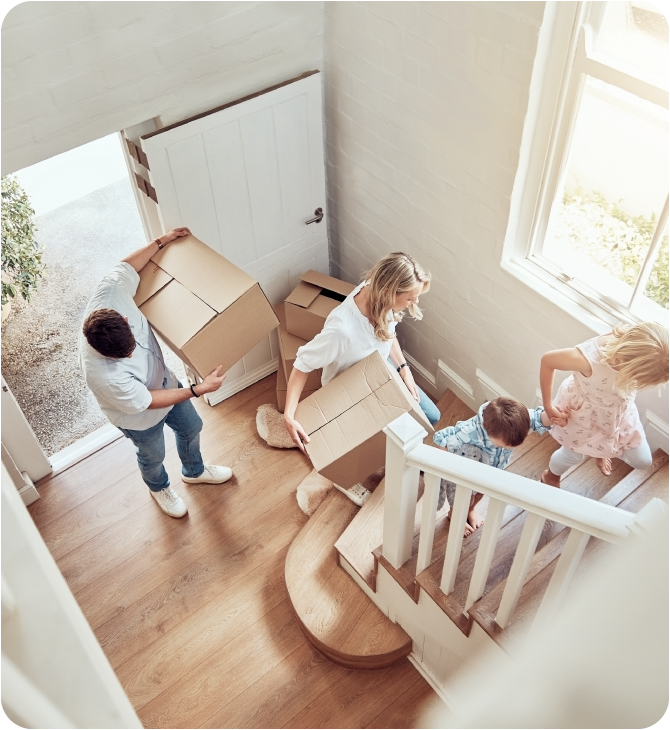 Parents and their children arriving at their newly insured rental home, carrying moving boxes.