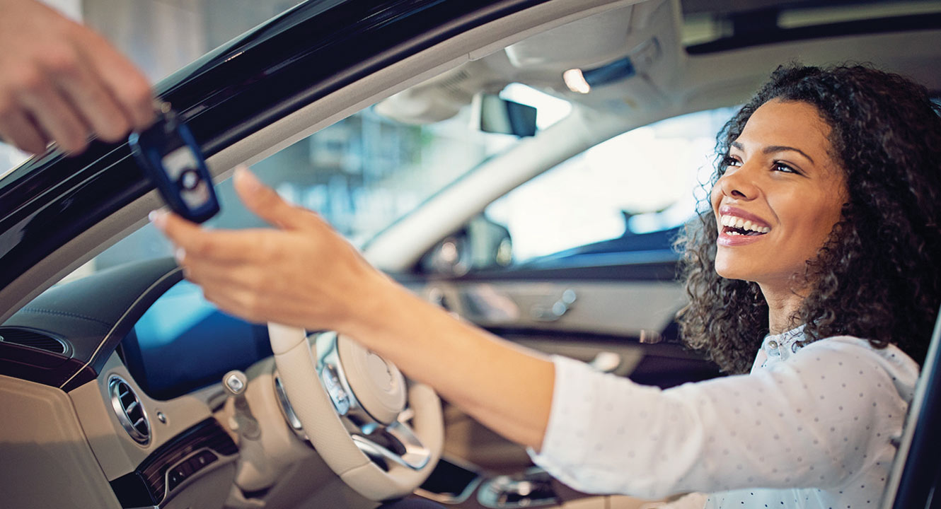 Young woman receiving the key to a new car.