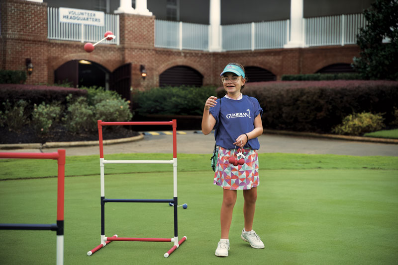 Young girl smiling while playing outdoors with Guardian Credit Union shirt.
