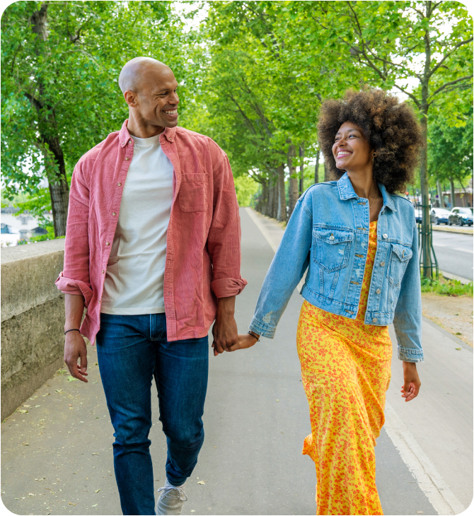 Smiling couple walking hand-in-hand on the sidewalk, happy to be free from financial worries.