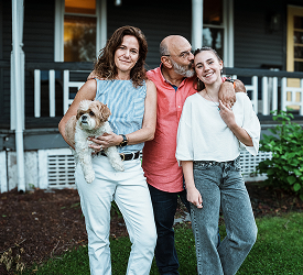 Smiling family with dog in front of their home, representing Guardian CU’s home insurance options for protection and peace of mind